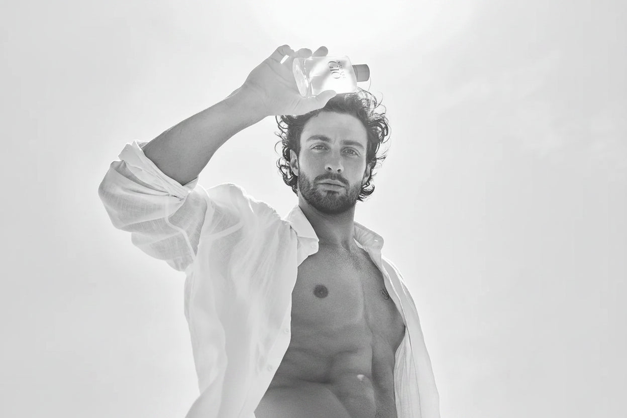 Man holding a perfume bottle against a white background