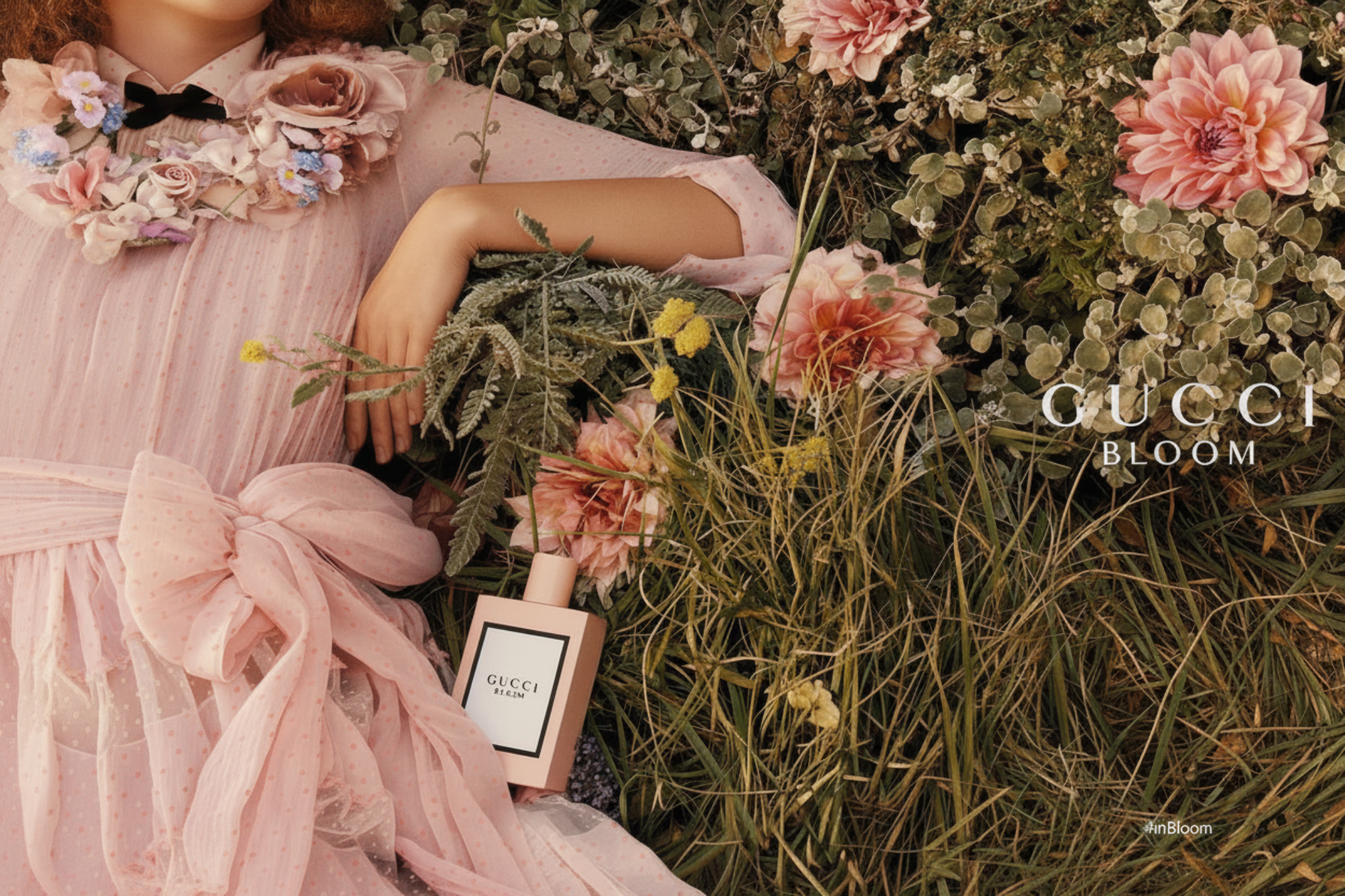 Person in a pink dress surrounded by flowers with Gucci Bloom perfume bottle.